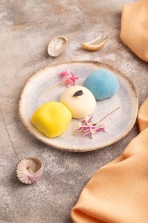 Japanese Mochi Cakes on brown concrete background and orange textile, side view, close up