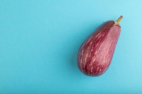 Purple eggplant with white stripes on blue pastel background. Top view, flat lay, copy space.