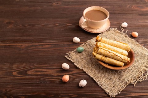 Waffles with caramel on brown wooden background and linen textile, cup of coffee, side view, Copy