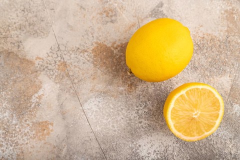 Yellow Lemon Cut in half on brown concrete background. Top view, flat lay, copy space. healthy