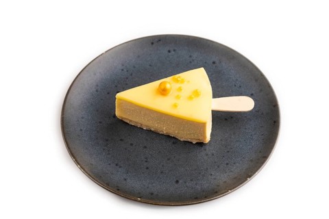 Yellow Cake pop with sprinkles on blue ceramic plate isolated on white background, side view, close