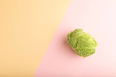 Green lettuce on pink and orange pastel paper background. Top view, copy space, flat lay. healthy