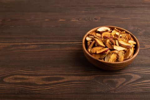 Dried Apples in wooden bowl on brown wooden background. Side view, copy space, healthy food,