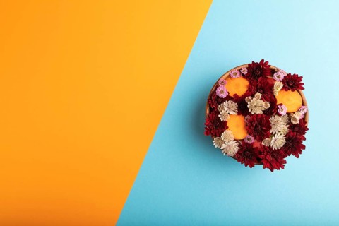 Wooden bowl with carrot slices and red Chrysanthemum flowers, Astrantia flowers, flower salad on