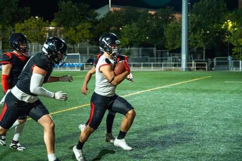 American football player is running with the ball, while teammates are blocking opponents during an