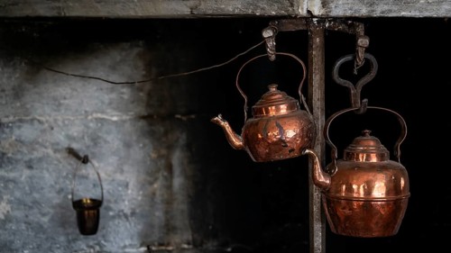 Alte Kupferkessel, die an Haken in einer rustikalen Küche hängen, historischer Bauernhof und