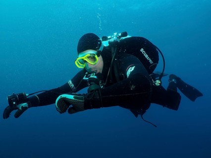 Ein Taucher in voller Ausrüstung kontrolliert unter Wasser seinen Tauchcomputer. Tauchplatz Wrack