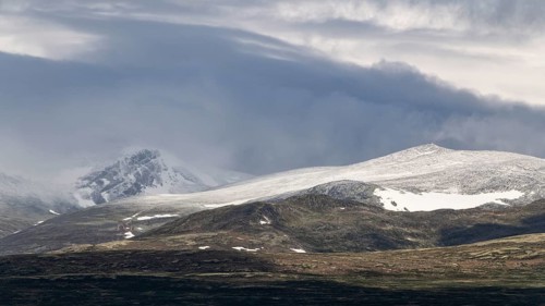 Blick auf schneebedeckte Berggipfel und baumlose Landschaft, Wolken, Pilgerweg Olavsweg, Olavsleden