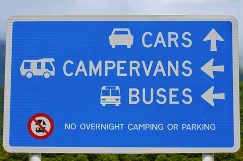 Ein Schild zeigt die Richtung für Autos, Wohnmobile und Busse und verbietet Übernachtcamping oder