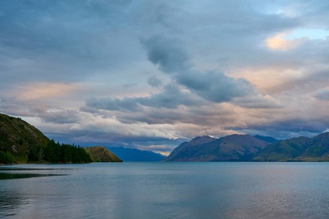 Friedlicher See mit Bergpanorama und bewölktem Himmel kurz vor Sonnenuntergang, Lake Hawea, Hawea,