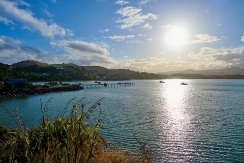 Das Sonnenlicht reflektiert auf dem Meer mit Booten und einem Pier, Moeraki, Hampden, North Otago,
