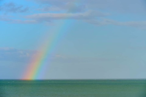 Ein Regenbogen über dem blauen Meer unter einem wolkigen Himmel, Moeraki, Hampden, North Otago,