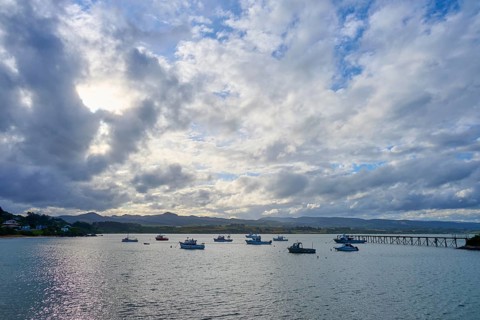 Boote auf ruhigem Wasser unter einem bewölkten Himmel bei Sonnenuntergang, Moeraki, Hampden, North