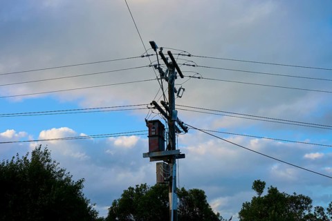 Ein Strommast mit Kabeln unter einem teils bewölkten, sonnigen Himmel, Moeraki, Hampden, North