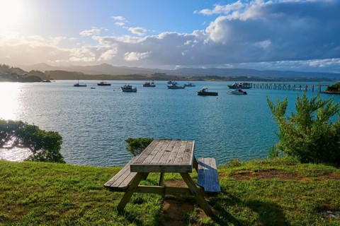 Ein Picknicktisch auf einem Hügel mit Blick auf Boote im Wasser, Moeraki, Hampden, North Otago,