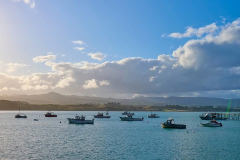 Boote auf einem sonnigen Gewässer mit einer Wolkenlandschaft im Hintergrund, Moeraki, Hampden,