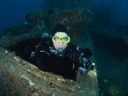 Diver looking out of the hatch of a wreck. Dive site wreck of the Vis, Pula, Croatia, Mediterranean