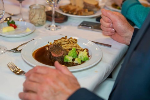 Steak with vegetables and chips, presented on a festively laid table with a white tablecloth