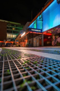 Illuminated urban scene at night with modern buildings and coloured neon lights, Tesla Model Y