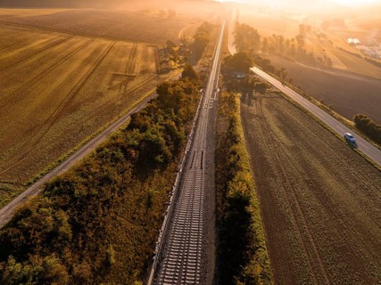 View of railway tracks and neighbouring fields at sunrise in golden light, Hermann Hesse Railway,