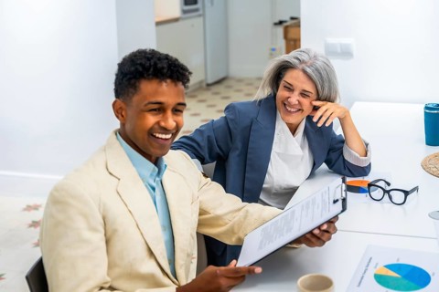 Diverse business professionals sharing a moment of laughter while reviewing documents, fostering