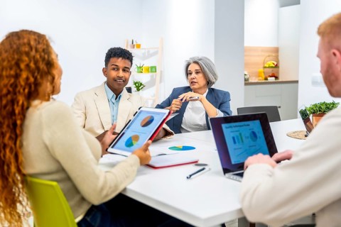 Multiethnic business professionals collaborating around a table, sharing insights from digital