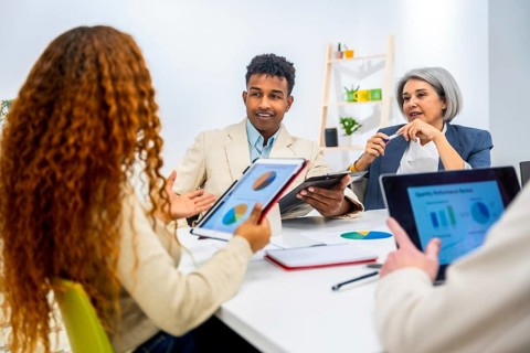 Business professionals discussing financial data and charts on digital tablets and paper during a