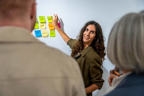 Young woman presenting business concepts and brainstorming ideas to colleagues using colorful
