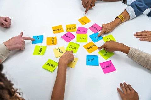 Diverse business professionals collaborating, pointing at colorful sticky notes with written