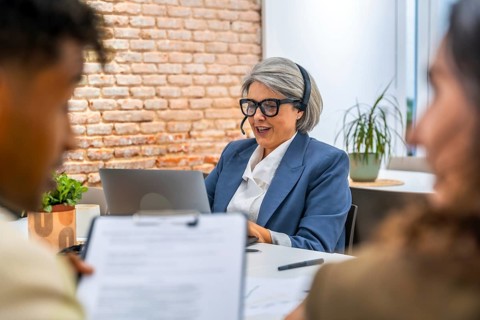 Senior businesswoman with a headset providing attentive customer service and digital support while