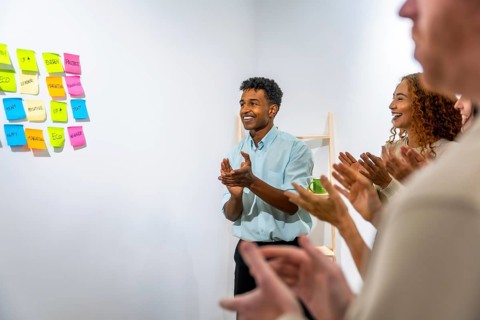 Smiling business team members are clapping, showing appreciation and recognition during a