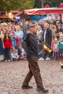 A juggling artist performs fire tricks in front of an interested audience, Feuernacht,