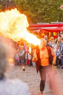 A man breathes fire during a show, surrounded by an attentive audience at a festival, Feuernacht,