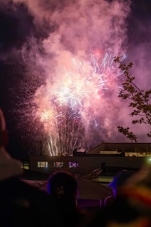 Colourful fireworks in the night sky during a celebration, the scene is accompanied by smoke and