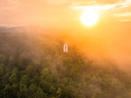 A lone tower rises out of a misty forest, illuminated by a warm sunset, Schönbergturm, Pfullingen,