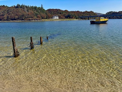 Clear lake surface with a yellow boat and wooden houses on the shore, Silver Sands of Morar, Morar,