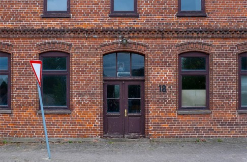 View of the entrance area of a brick building with a leaning traffic sign in front of it, Uenzen,