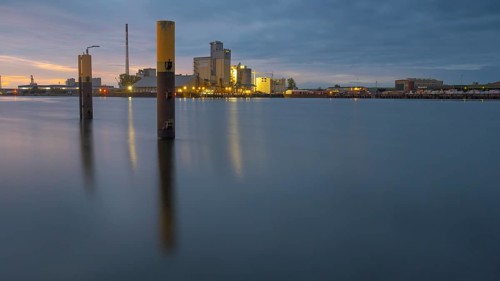 View across the Weser past dolphins to an industrial area in the evening light, Gröpelingen,