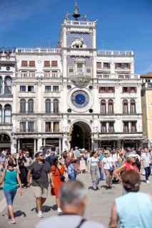 Venice, Italy - 3 September 2025: Tourists at the clock tower of San Marco on St Mark's Square in