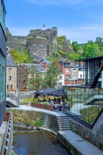 Tourists at restaurant along the river Ourthe and ruined castle in the city La Roche-en-Ardenne,