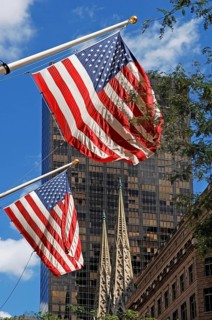 Waving USA flags, behind towers of St Patrick's Cathedral, Manhattan, New York City, USA