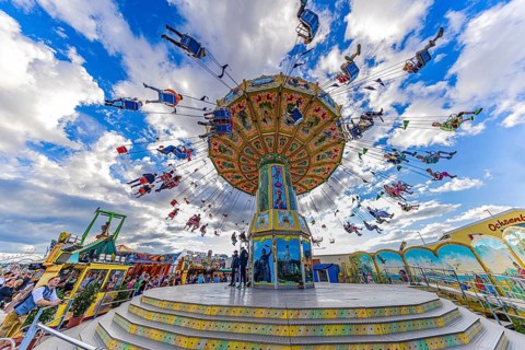 Chain carousel in motion in front of a white-blue sky, Theresienwiese, Oktoberfest, Munich, Upper