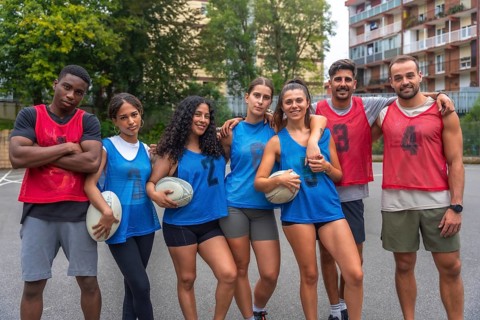 Multi ethnic rugby team posing together with their arms around each other's shoulders, holding