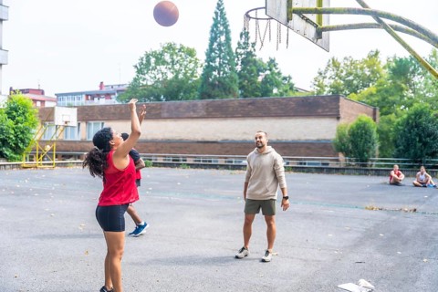 Young woman practicing basketball shooting at the hoop under the supervision of her coach on an
