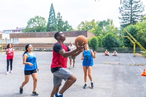 Group of diverse basketball players enjoying a lively game on an outdoor court, highlighting