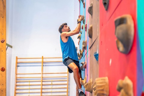 Young sportsman ascending a vibrant climbing wall, showcasing strength, agility, and intense focus