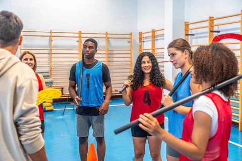 Multi ethnic floorball team gathered in a gym, attentively listening to their coach's instructions