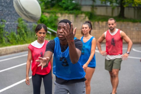 Rugby player wearing a blue training bib is catching a ball during practice, surrounded by