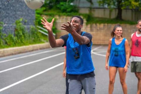 Young male athlete wearing a blue training bib catching a rugby ball during practice, with his