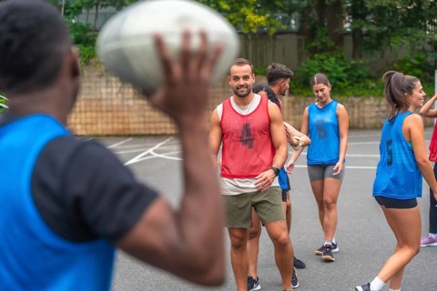 Group of athletes in sportswear engaging in passing drills while training on an outdoor court,